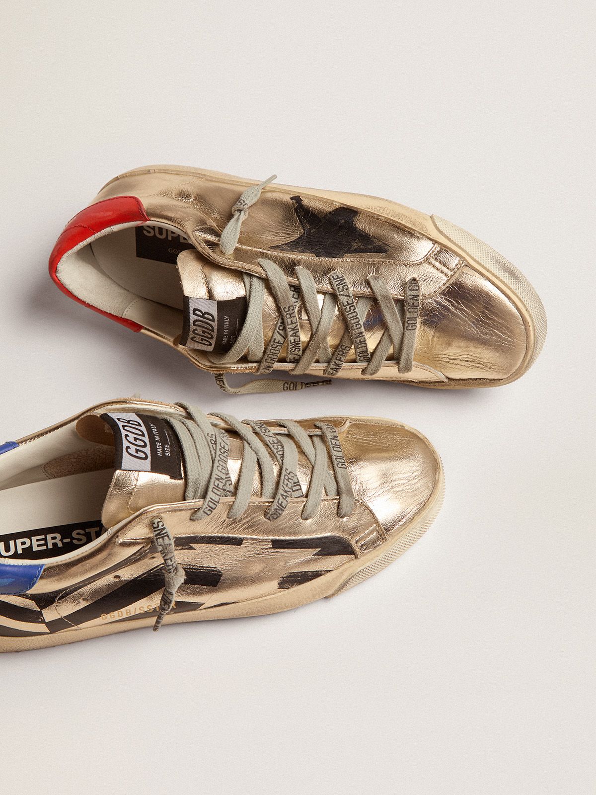 Sup-S sneakers in platinum-colored laminated leather with black flag print and red and blue heel tab